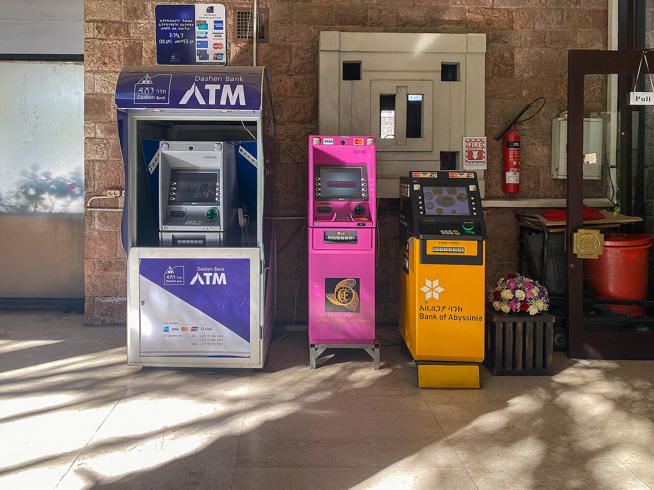 Three bank ATMs side by side in a hotel lobby